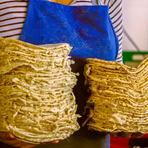 Una mujer sosteniendo dos montos de tortillas